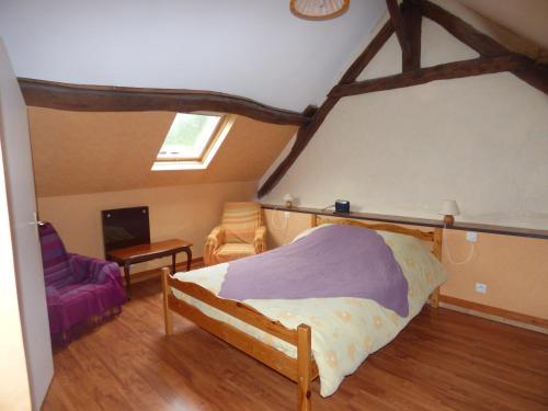 a bedroom with a bed and a purple chair at La Ferme du Manoir Etretat in Bordeaux-Saint-Clair