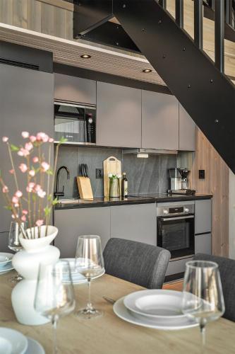a dining room table with chairs and a kitchen at Rorbuleilighet Lysøysundet 1G in Henningsvær