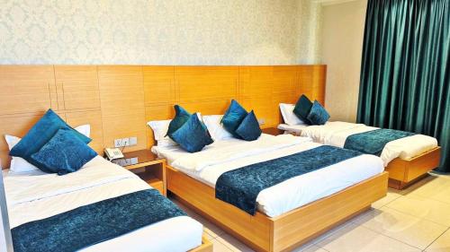 a hotel room with two beds with blue pillows at فندق الملك - King Hotel in Karbalāʼ