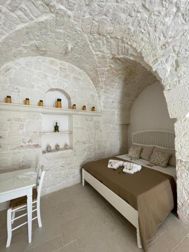 a bedroom with a bed and a table in a stone wall at L'hammam tra le volte a stella in Ceglie Messapica