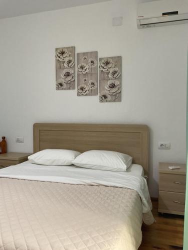 a bed in a bedroom with three pictures on the wall at Garden Holiday Studios in Himare