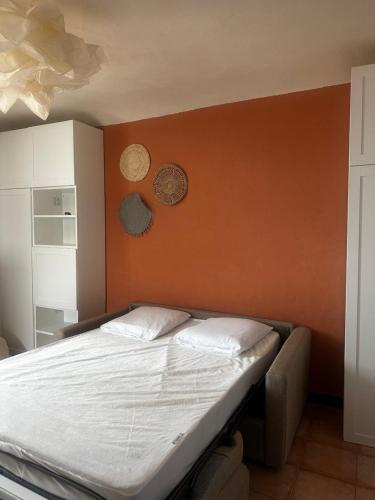 Ce lit se trouve dans un dortoir doté d'un mur orange. dans l'établissement Studio Climatisé Hyper Centre Ajaccio, à Ajaccio