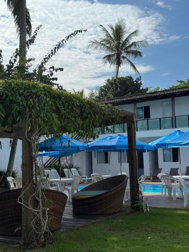 a resort with chairs and umbrellas and a pool at Pousada Point Beach - Acácias in Guarujá