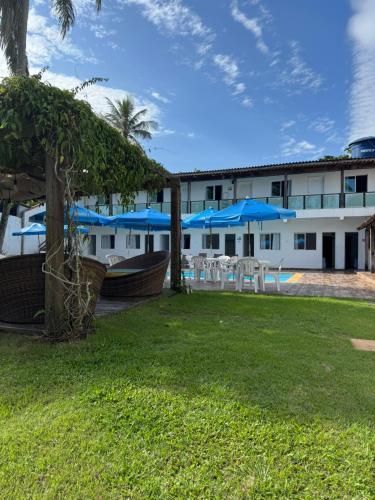 a resort with tables and blue umbrellas in a yard at Pousada Point Beach - Acácias in Guarujá
