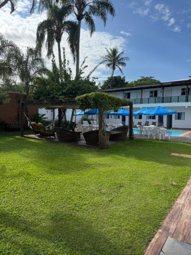 a yard with chairs and umbrellas and a pool at Pousada Point Beach - Acácias in Guarujá