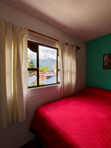 a bedroom with a red bed and a window at Hospedaje Teponaztle in Tepoztlán