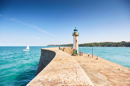 un faro su un molo con una barca in acqua di Chambre d'hôte Le Grand Large a Binic