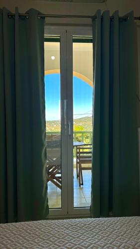 a bedroom door with a view of a balcony at Serene Livadi Apartment in Kýthira
