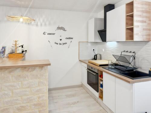 a kitchen with white cabinets and a counter top at Appartement rénové, lumineux au centre de Vic in Vic-sur-Cère