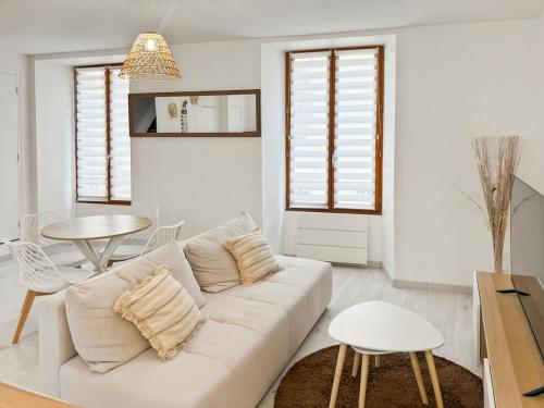a white living room with a white couch and a table at Appartement rénové, lumineux au centre de Vic in Vic-sur-Cère