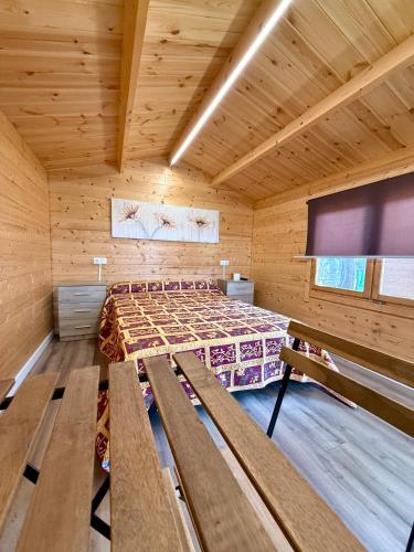 a room with a bed and benches in a cabin at Camping Fraga Balada in Porto do Son