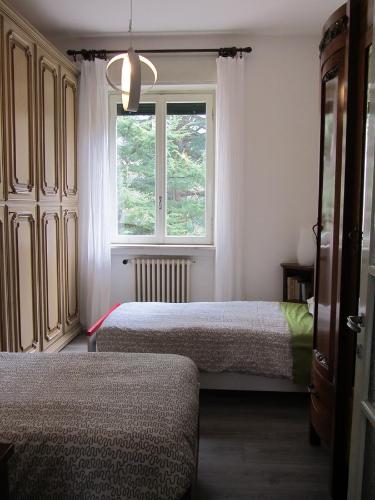 Appartamento Maglio في Canzo: غرفة نوم بسريرين ونافذة