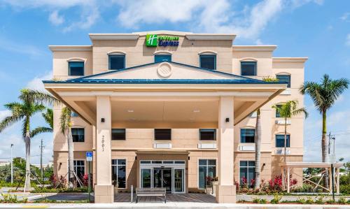 a hotel front of a building with palm trees at Holiday Inn Express & Suites Boynton Beach West by IHG in Boynton Beach