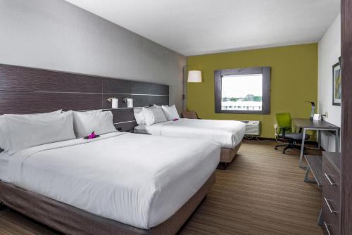 a hotel room with two beds and a desk at Holiday Inn Express & Suites Boynton Beach West by IHG in Boynton Beach