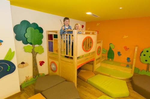 a child standing in a bunk bed in a room at AIGO Welcome Family Resort in Aigen im Mühlkreis