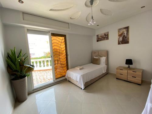 a bedroom with a bed and a large window at Duplex - Pool and Beach in Dar Hamida