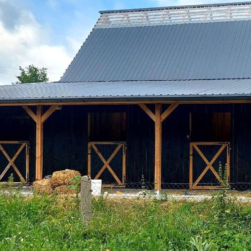 a black barn with wooden doors and a black roof at Happy Horse Sosnowa Góra 