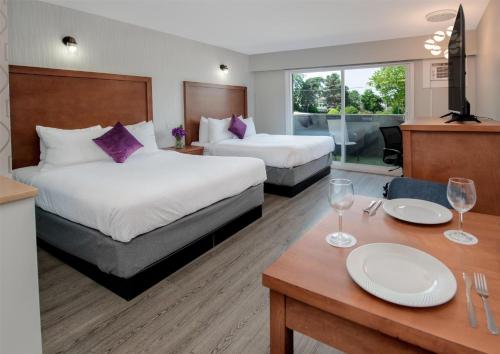 a hotel room with two beds and a table with wine glasses at Coast Metro Vancouver Hotel in Burnaby