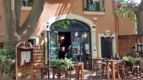 a restaurant with tables and chairs in front of a building at Chambres d'Hôtes Le Mimosa in Saint-Saturnin-de-Lucian