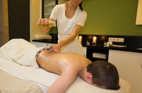 a woman giving a man a bath in a hotel room at AIGO Welcome Family Resort in Aigen im Mühlkreis
