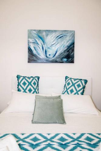 a white bed with a painting on the wall at Miro B&B in Lecce