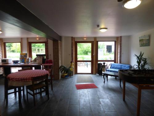 a living room with a table and chairs and windows at La Ferme du Manoir Etretat in Bordeaux-Saint-Clair