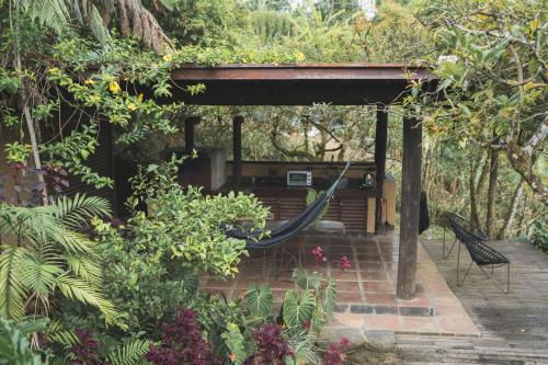 a porch with a hammock in a garden at Cabañas en la montaña Viga Vieja in San Peregrino