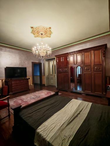 a bedroom with a large bed and a chandelier at Nostalgia Old City Bucharest in Bucharest