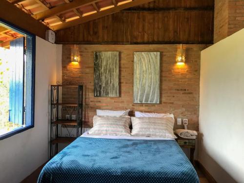 a bedroom with a blue bed and a brick wall at Chalé Frida Kahlo in Campinas