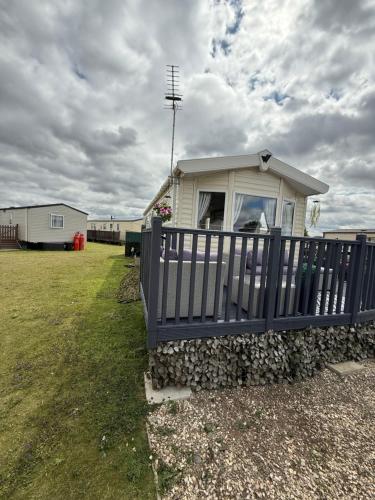 a small house with a fence and a yard at Andreas Fir Trees Retreat at 7 Lakes Country Park in Crowle