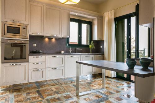 a kitchen with white cabinets and a table in it at Pleiades Luxury Villa in Svoronata