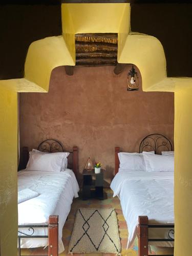 two beds sitting next to each other in a bedroom at Dar Imane - Magnifique ferme en pleine nature in Ouarzazate