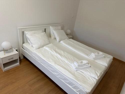 a white bed with white sheets and towels on it at Apartmán 7 - Petřín in Karlovy Vary