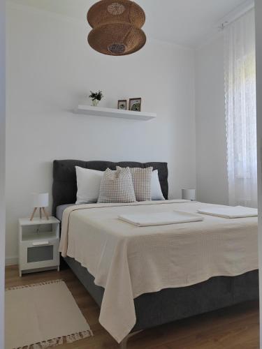 a white bedroom with a large bed with white sheets at Apartman Lola Palić II in Palić