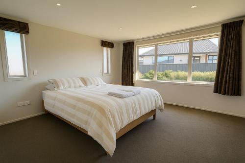 a bedroom with a bed and a large window at West Meadows Escape, Lake & Slopes Minutes Away in Wanaka