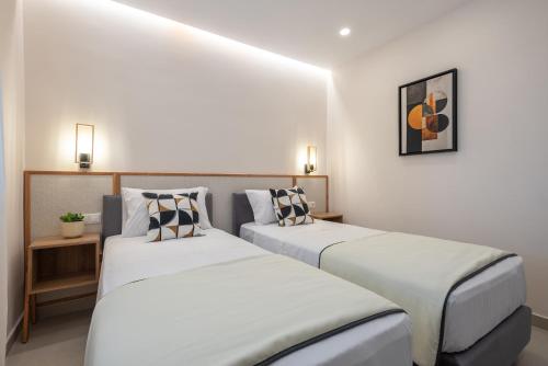 two beds in a room with white walls at Alysos Luxurious Apartments in Mirina