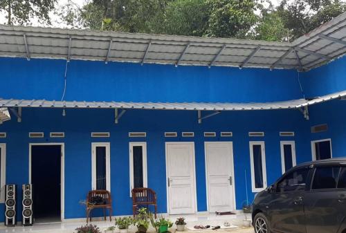 a blue building with white doors and chairs at Villa Daenk Bogor in Cinagara