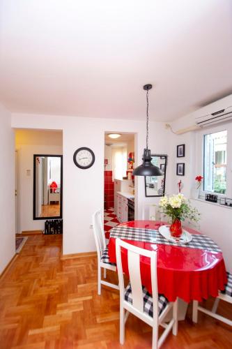 a kitchen and dining room with a red table and chairs at Casa Mimosa Bright and Soulful in Budva