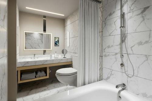 a bathroom with a toilet and a sink and a tub at The Westin Galleria Dallas in Dallas
