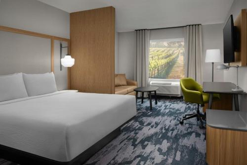 a hotel room with a bed and a chair and a window at Fairfield by Marriott Inn & Suites Portland Newberg in Newberg