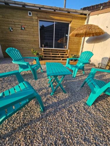 a group of blue picnic tables and an umbrella at Love room L'écrin tropical in Aubers