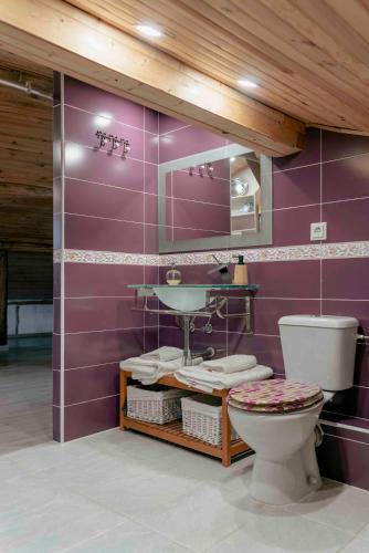 a purple bathroom with a toilet and a sink at Suite La Mansion Casa Rural in La Toba