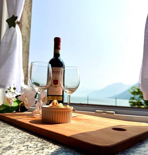 a table with a bottle of wine and two glasses at Como Lake View Enjoy&Relax in Brienno