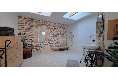 une salle de bain avec un lavabo et un mur en pierre dans l'établissement L'intemporelle, à Saint Dionizy