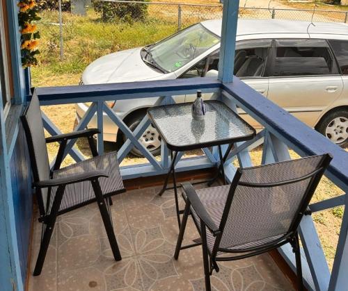 a table and chairs on a balcony with a car at AJs Cottage Escape in Potters Village