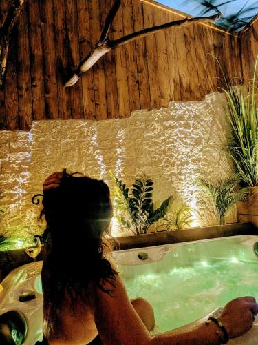 a woman sitting in a jacuzzi tub with plants at Les Spas de la mer, Appart&Spa Canopée, 100m de la plage, Love Room in Le Grau-du-Roi