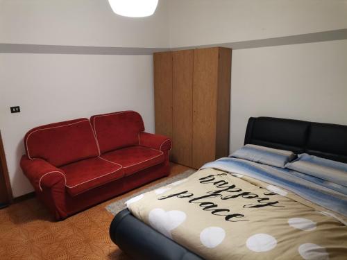 a bedroom with a bed and a red couch at Apparemment in zona residenziale in Pordenone