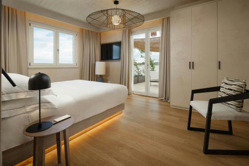 a bedroom with a large bed and a chair at Cala Ponte, a Tribute Portfolio Hotel in Polignano a Mare