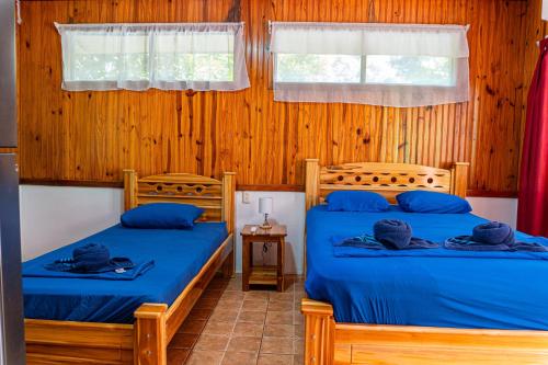 two beds in a room with wooden walls at Corcovado & Drake Inn in Drake