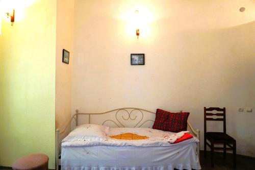 a small bedroom with a bed and a chair at Pospolita Guest House in Kutaisi